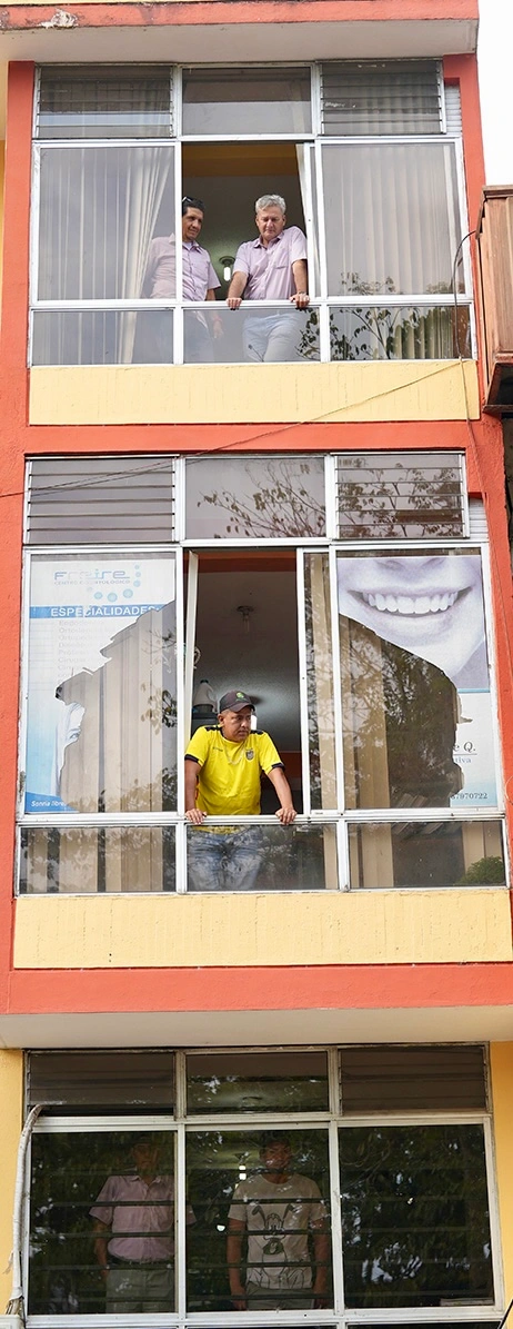 edificio de tres pisos con una persona en cada ventana