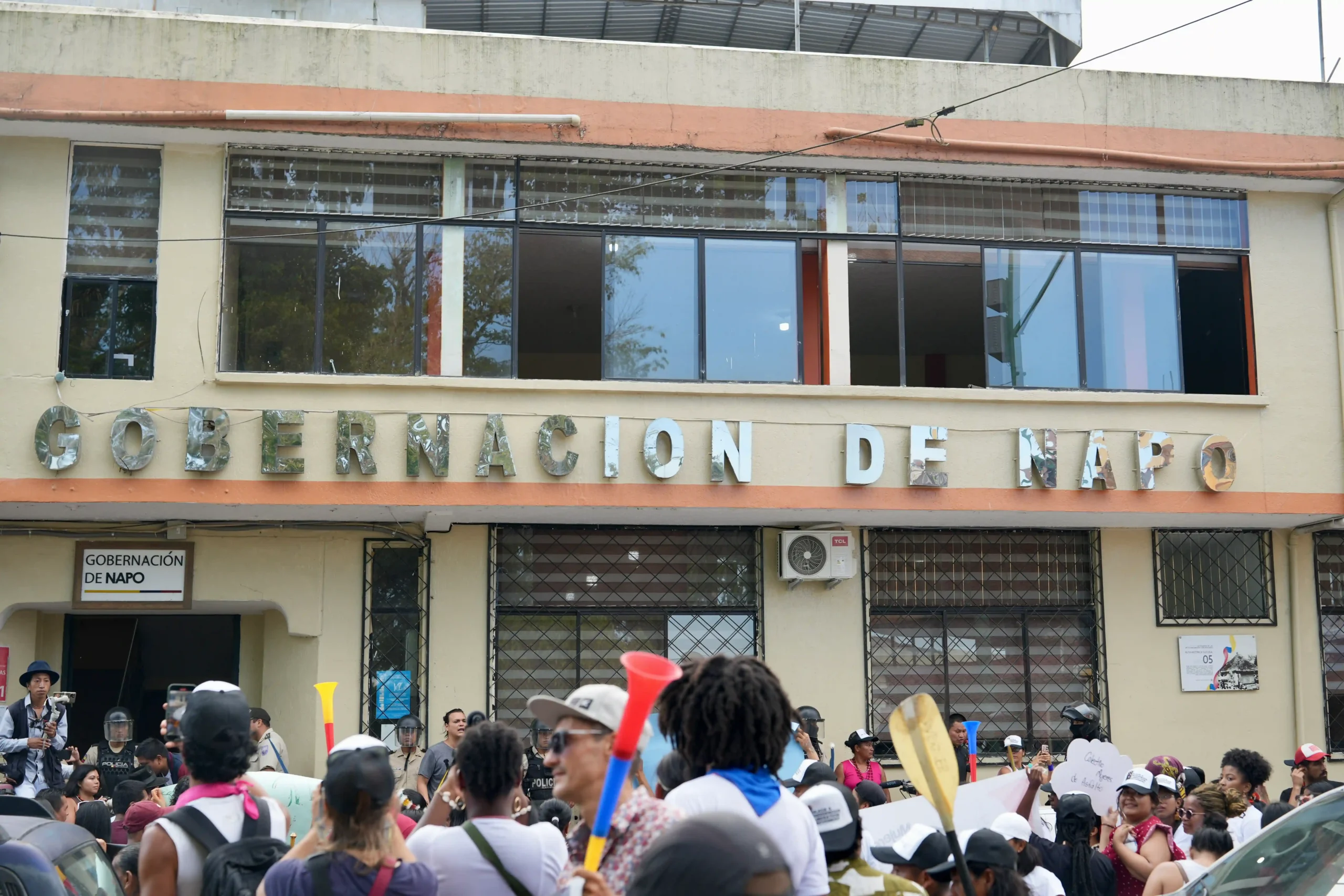 muchas personas con cornetas frente a una institución