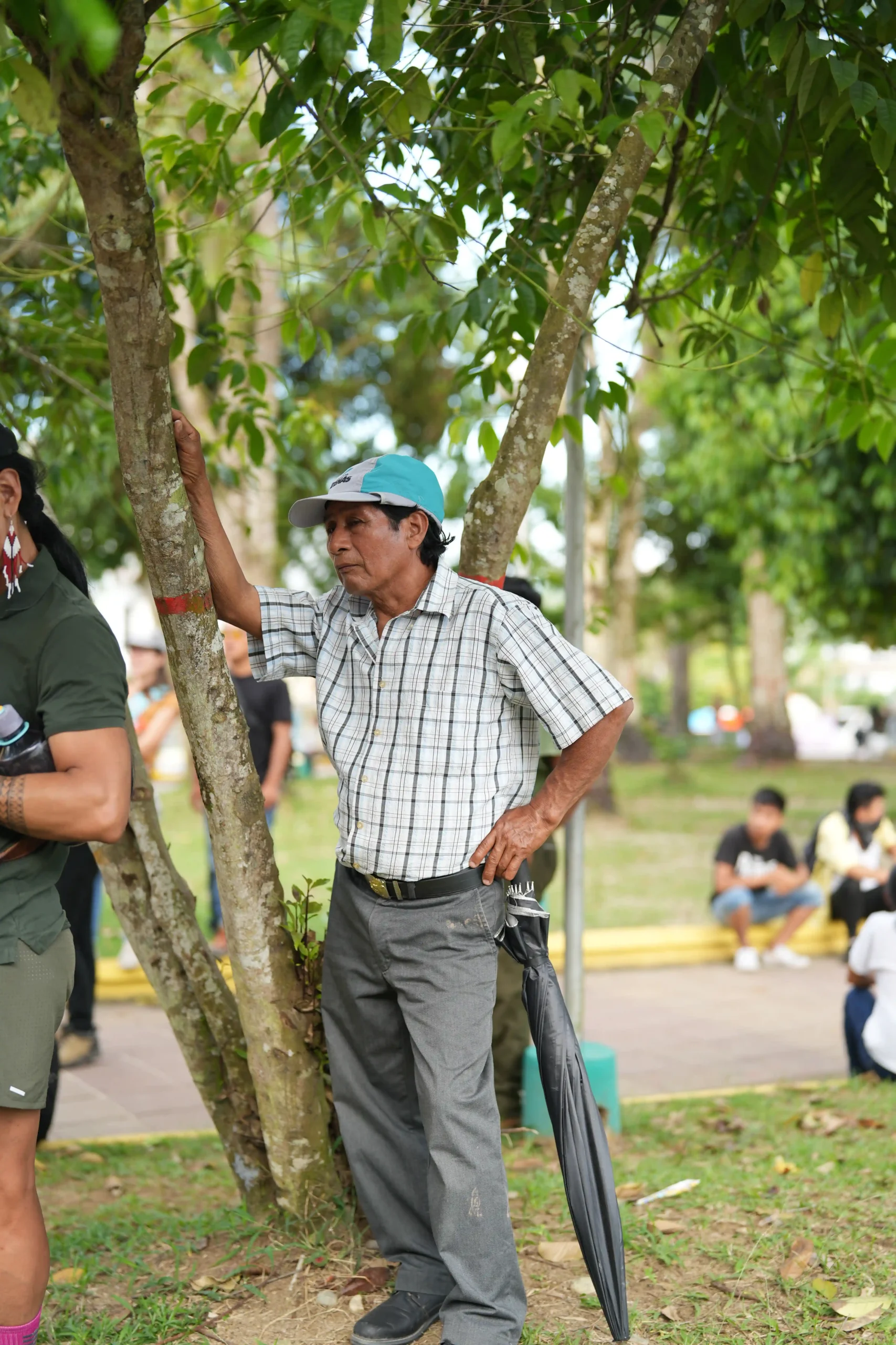 adulto con gorra apoyado sobre un arbol