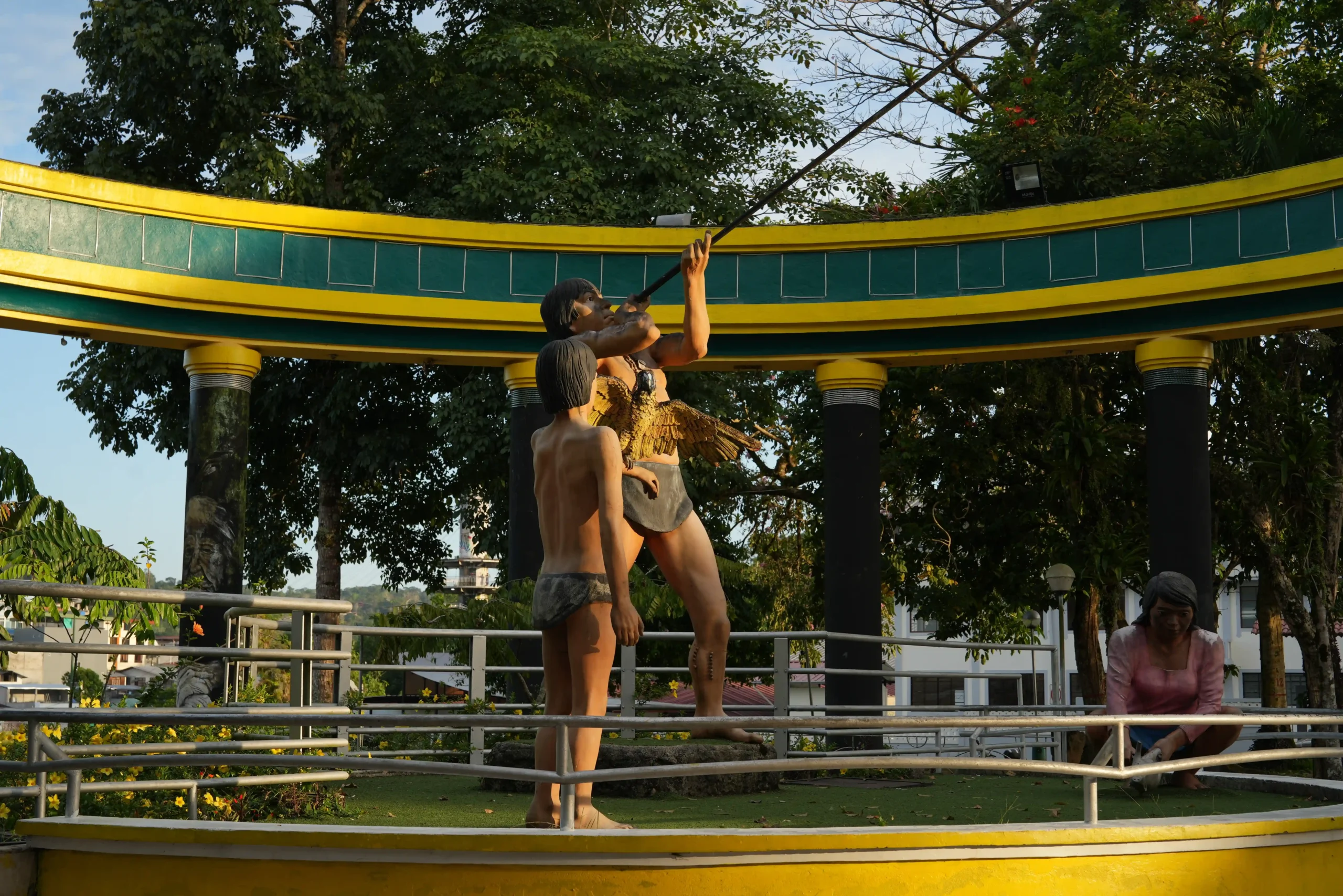 estatuas de tres personas una disparando una cerbatana un niño viendo y una mujer sembrando