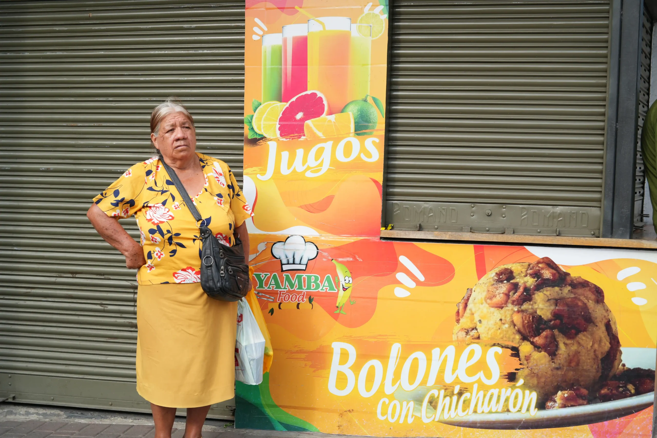 señora vestida de amarillo junto a una tienda de comida
