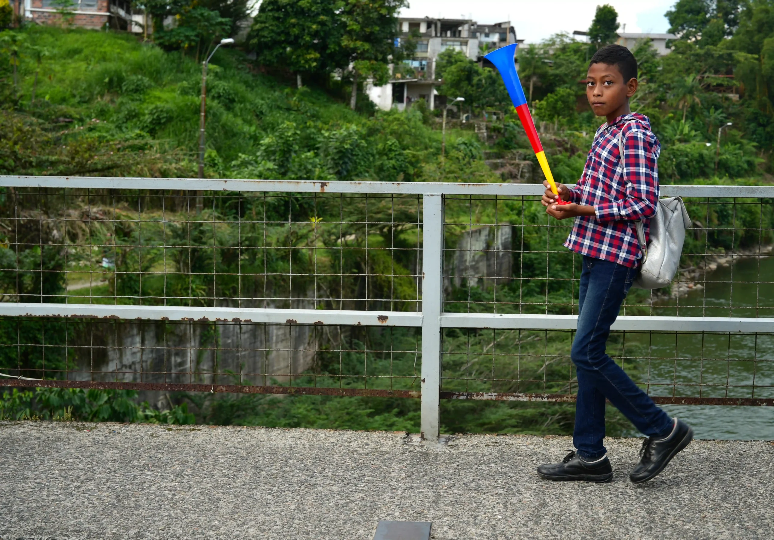 niño caminando en un puente sosteniendo una corneta